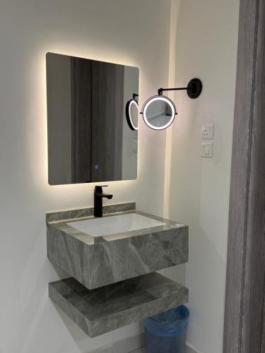 a bathroom with a stone sink and a mirror at شقة بغرفة معيشة وغرفة نوم in Buraydah