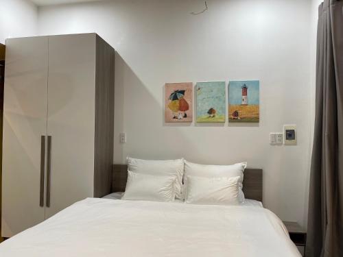 a bedroom with a white bed and some pictures on the wall at Tehya Villa in Da Nang