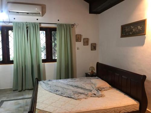 a bedroom with a bed with green curtains at Malgedara in Badulla