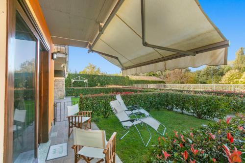 eine Terrasse mit Stühlen, einem Tisch und einem Sonnenschirm in der Unterkunft Blu Oltrelago Pool & Lake - Happy Rentals in Leggiuno