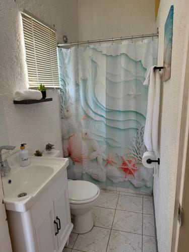 a bathroom with a toilet and a shower curtain at Superstar Living in Treasure Beach