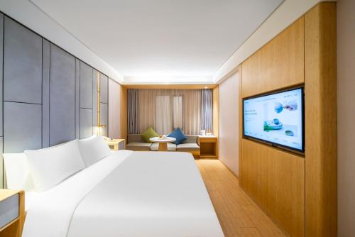 ein Hotelzimmer mit Bett und Flachbildfernseher in der Unterkunft JI Hotel Shanghai Wujiaochang Wanda Plaza in Shanghai