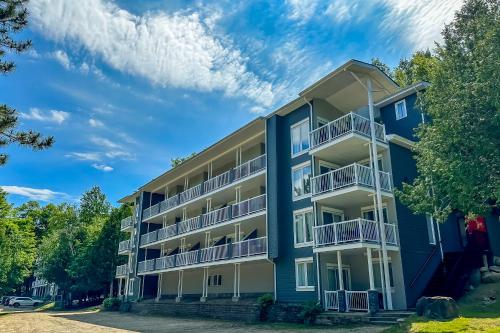 a blue apartment building with balconies and trees at Le Lightroom by Gestion ELITE in Mont-Tremblant