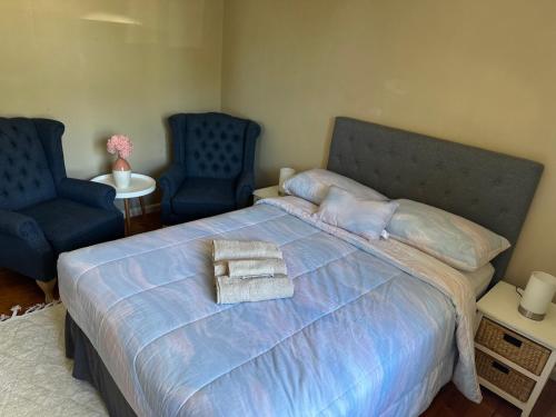 Canberra Hospital Locum Welcome Entire Family Home في Phillip: غرفة نوم بسرير كبير مع كرسيين ازرق