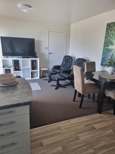 a living room with chairs and a table and a television at Bethlehem Apartment in Tauranga