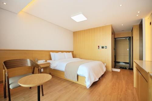 a hotel room with a bed and a desk and a table at Noble Hotel in Yeosu