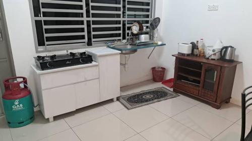 a kitchen with a sink and a stove and a table at Sakeena Homestay in Padang Serai
