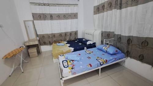 a bedroom with two beds and a table in it at Sakeena Homestay in Padang Serai