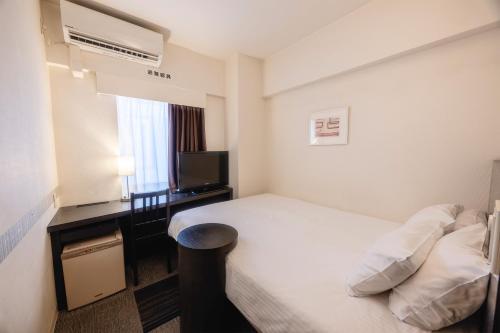 a hotel room with a bed and a television at KOKO HOTEL Yokohama Tsurumi in Yokohama