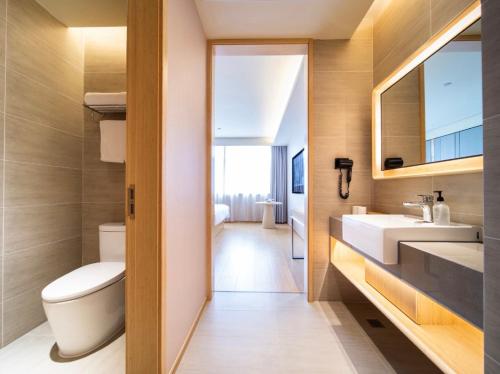 a bathroom with a toilet and a sink and a mirror at JI Hotel Hangzhou Banshan Road in Hangzhou