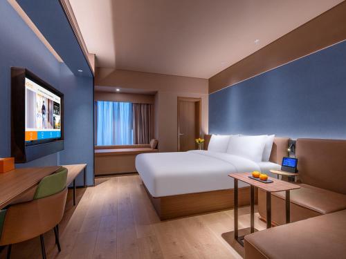 een hotelkamer met een groot bed en een bank bij Orange Chengdu Jinniu Wanda Hotel in Chengdu