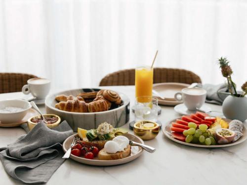 a table with plates of food and a bowl of fruit at Elysium Noosa Resort - MGallery Collection in Noosa Heads