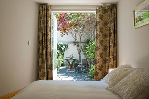 een slaapkamer met een raam met uitzicht op een tuin bij Stella Bed & Breakfast in Mexico-Stad