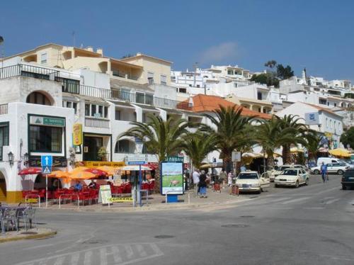 a city street with cars and palm trees and buildings at Casa Kelly in Carvoeiro