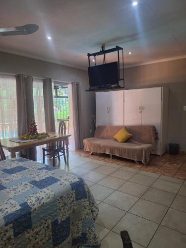 a bedroom with a bed and a table and a couch at SMAPERS GUESTHOUSE in Brits