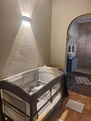 a bathroom with a bed with a light on the wall at SMAPERS GUESTHOUSE in Brits