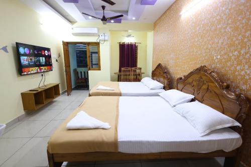a bedroom with two beds and a flat screen tv at Bluetique Beach House in Kuilapayam