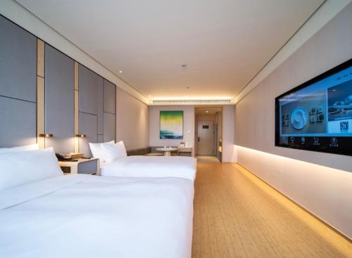 two beds in a hotel room with a flat screen tv at JI Hotel Hangzhou Banshan Road in Hangzhou