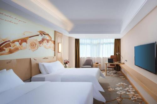 a hotel room with two beds and a flat screen tv at Vienna Hotel Shandong Dezhou Government Shopping Plaza in Songguantun