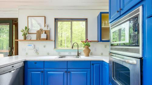 a blue kitchen with a sink and a microwave at Half Moon by AvantStay 4BR Cabin w Large Deck Yard w Patio Outdoor Dining in Great Barrington