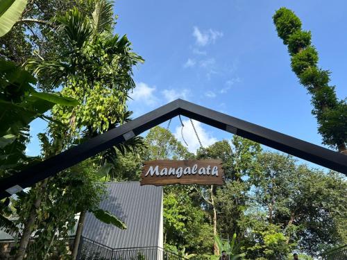 ein Schild für ein Restaurant mit Bäumen im Hintergrund in der Unterkunft Mangalath River View Resorts in Kodanad