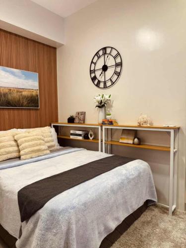 The Modern Nest Condo في مدينة سيبو: غرفة نوم مع ساعة كبيرة على الحائط