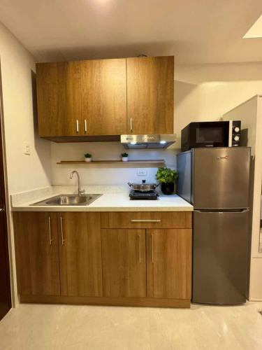 The Modern Nest Condo في مدينة سيبو: مطبخ مع خزائن خشبية وثلاجة من الفولاذ المقاوم للصدأ