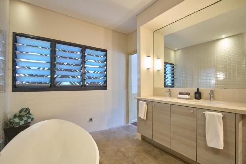 a bathroom with a toilet and a sink and a mirror at Pinctada Hotel Broome in Broome