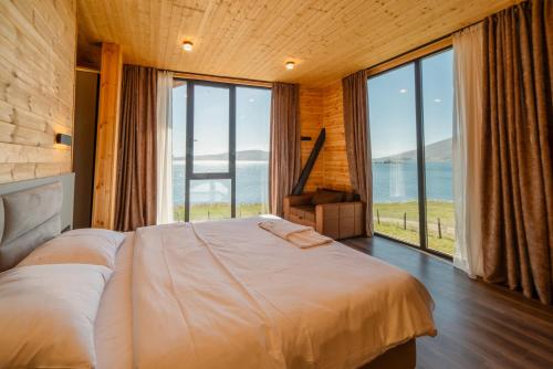 a bedroom with a large bed and large windows at Cottage Tabatskuri in Molit'i