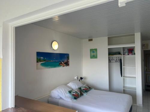 a white room with a bed and a mirror at Les Trois Ilets Location Studio Face a la Mer in Les Trois-Îlets