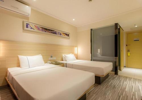 City Comfort Inn Wuhan Jiefang Avenue Xinrong Light Rail Station في ووهان: غرفة فندقية بسريرين ونافذة