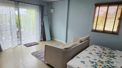 a living room with a couch and a large window at BaanMalee Homestay in Buriram