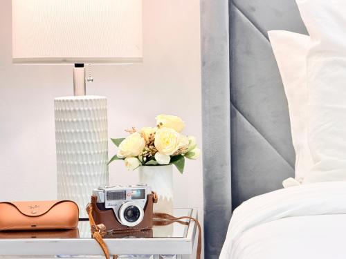 a table with a camera and flowers on a bed at Downtown 2B2B Apt! Near Convention Center & PPAC with Full Kitchen in Providence
