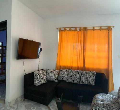 sala de estar con sofá negro frente a una ventana en Apartamento familiar Hergom - Grupos de 15 a 30 Pers, en Arboletes