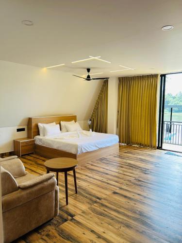 a bedroom with a bed and a couch and a table at Mangalath River View Resorts in Kodanad