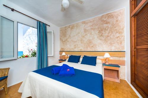 a bedroom with a bed with a blue hat on it at Comitas Tramontana Park in Fornells