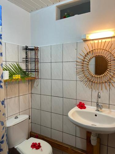 a bathroom with a sink and a toilet and a mirror at Pension Mave Mai in Nuku Hiva