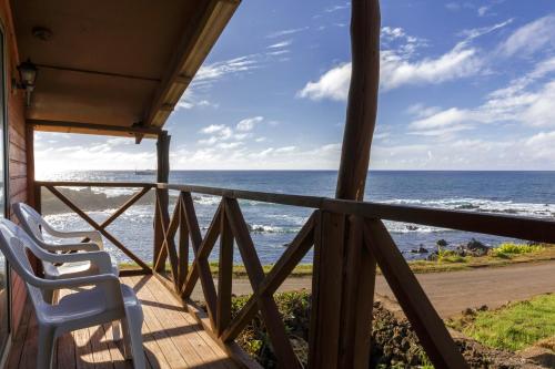 a porch with two chairs looking out at the ocean at Cabañas Matavai in Hanga Roa