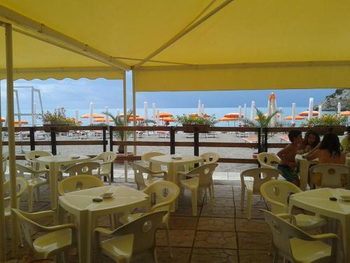 a restaurant with tables and chairs and a view of the water at Hotel Villa Degli Aranci in Maratea