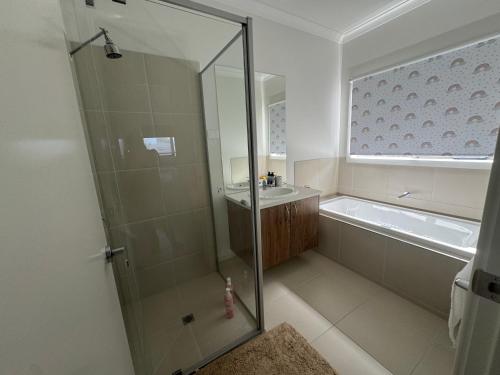 een badkamer met een douche, een wastafel en een bad bij Nine in Grovedale