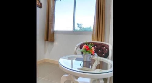 The Aam resort في بانغ ساري: طاولة زجاجية مع إناء من الزهور على كرسي