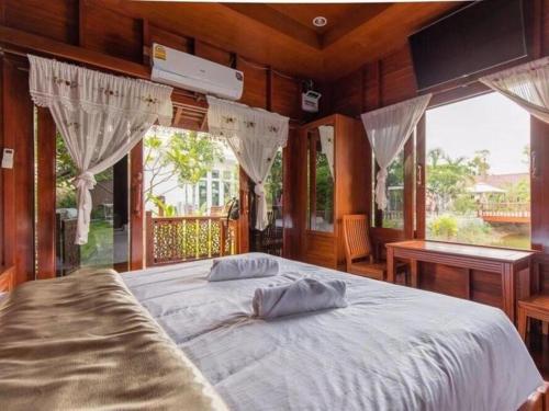 a bedroom with a large white bed with windows at Baan Kiangnam Pattaya Resort in Ban Pong