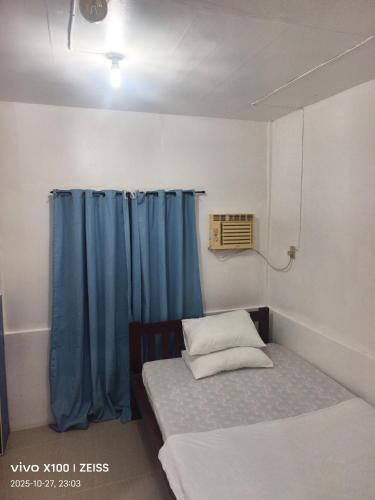 a small room with a bed and a blue curtain at Reefside Retreat by B'lu Bamboo in Moalboal
