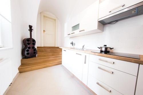 una cocina con armarios blancos y una guitarra de fondo en Three Golden Crowns Apartments en Praga