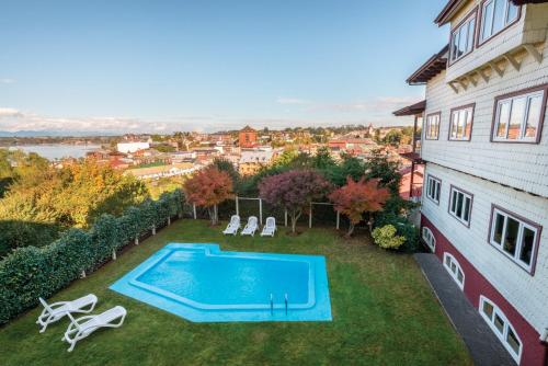 a backyard with a swimming pool and chairs and a building at Park Inn by Radisson Puerto Varas in Puerto Varas