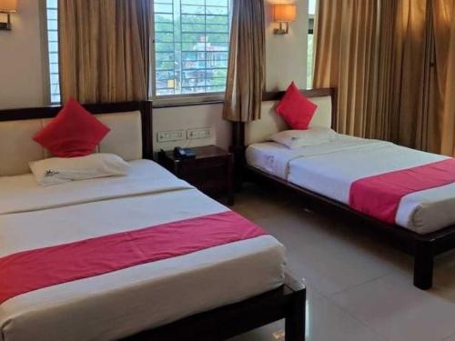 una camera d'albergo con due letti con cuscini rossi di Hotel O Jaipura Bus Terminal Formerly Navgun a Chattanahalli
