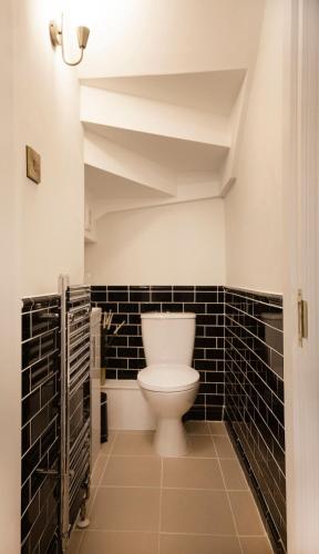 a bathroom with a toilet and black tiled walls at Grade II listed 3 bed townhouse in Exeter, Devon in Exeter