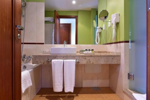 a bathroom with a sink and a tub and a mirror at Pestana Sao Tome in São Tomé