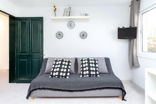 un lit avec des oreillers noirs et blancs et une porte verte dans l'établissement Tranquilo apto con preciosa cala, à Cala en Forcat