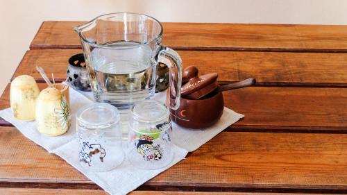 una jarra de vidrio y vasos de agua sobre una mesa en Coastal Home Muini Ūši, en Kolka